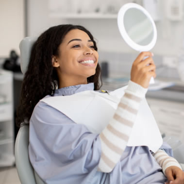 Lady looking in mirror at recently whitened teeth
